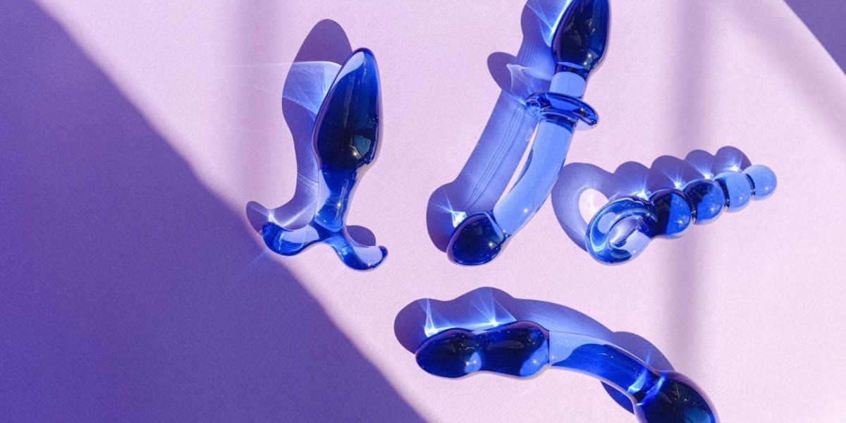 verschillende-glazen-dildos-roze-achtergrond